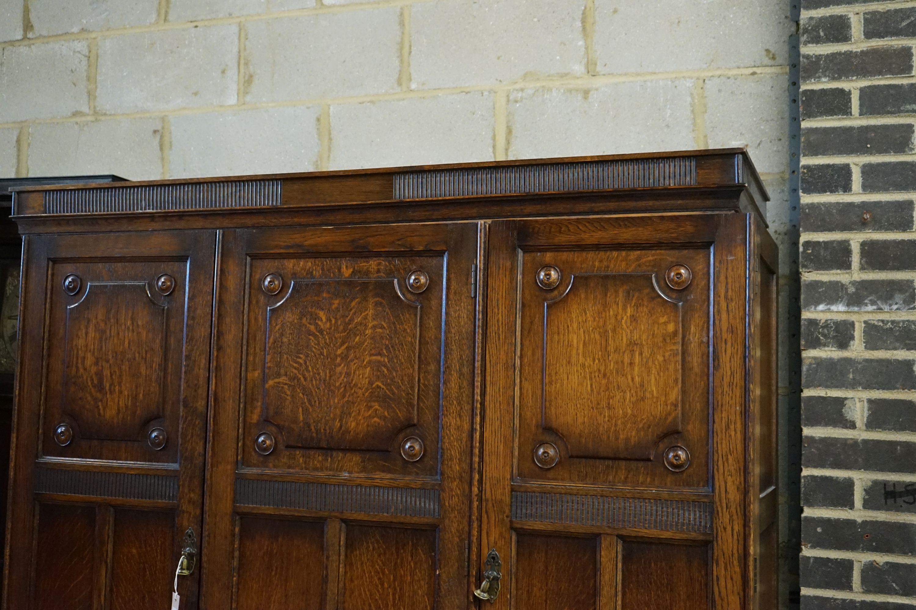 A carved and panelled oak triple wardrobe with fitted interior, length 150cm, depth 49cm, height 200cm